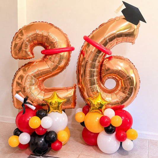 Gold number balloons with graduation cap and colorful base on a light background